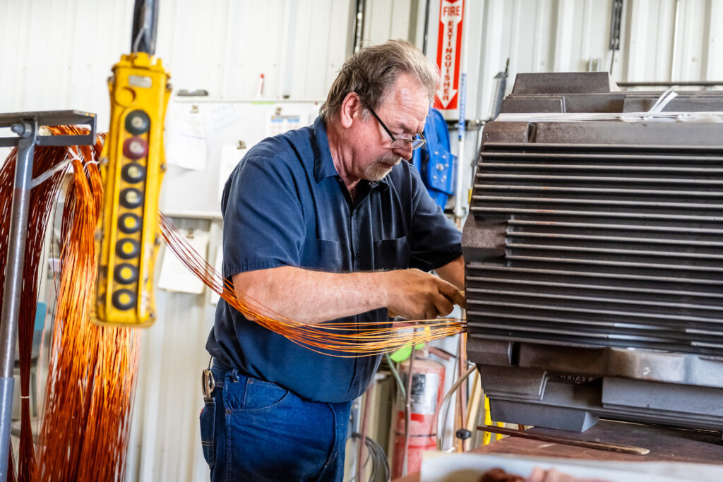 Technician winding copper coils on an industrial electric motor in a workshop